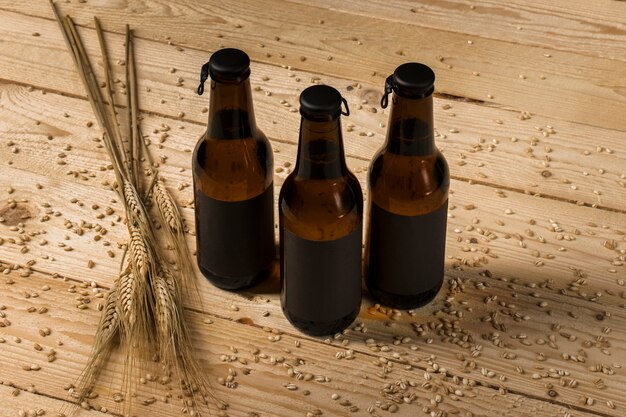 Три бутылки с алкоголем и колосья пшеницы на деревянной поверхности