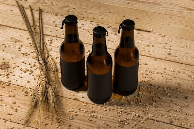 Three alcoholic bottles and ears of wheat on wooden surface