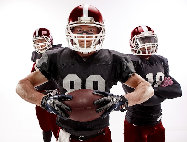 three american football players posing with ball on white