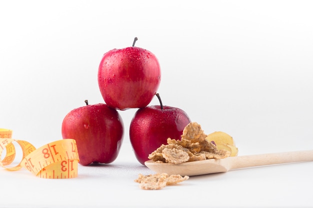 Three apples with measuring tape and cereals 