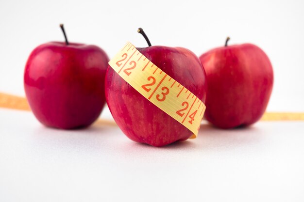 Three apples with measuring tape on table