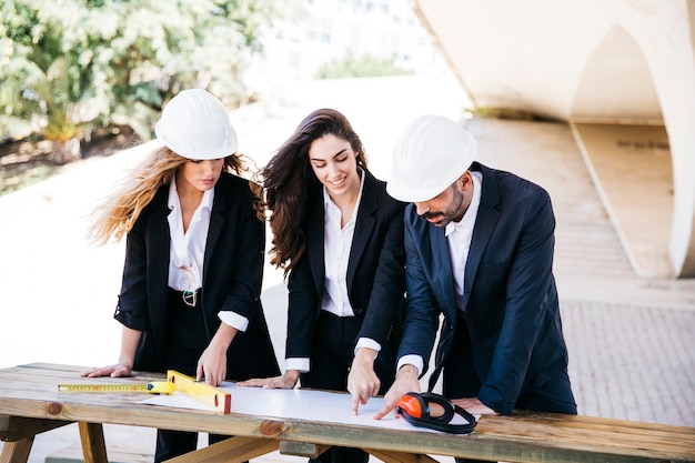 Free photo three architects with plan on table