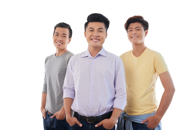 Three Asian men standing with hands in pockets and smiling for camera