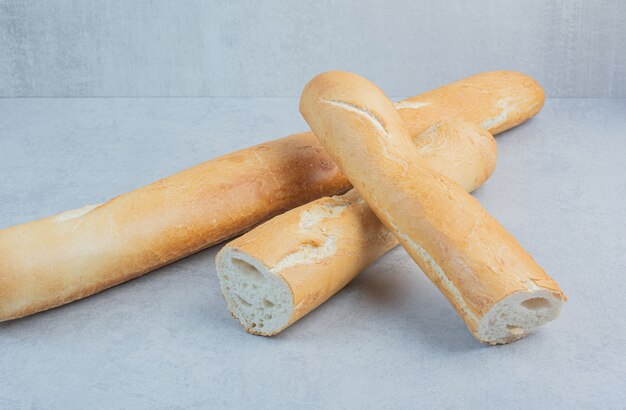 Три хлеба багета на мраморном фоне. Фото высокого качества