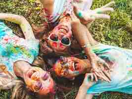 Free photo three beautiful smiling girls posing at holi party