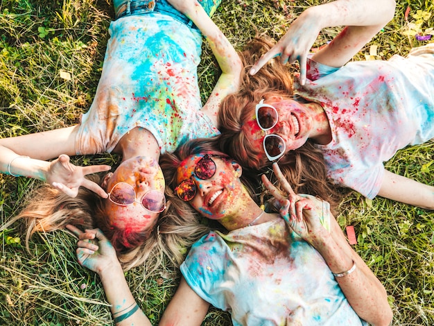 Free photo three beautiful smiling girls posing at holi party