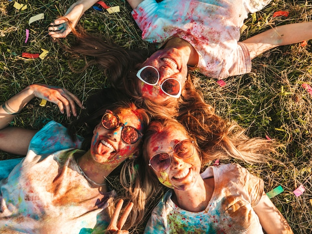 three beautiful smiling girls posing at holi party