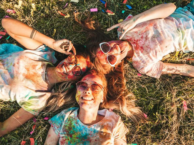 three beautiful smiling girls posing at holi party