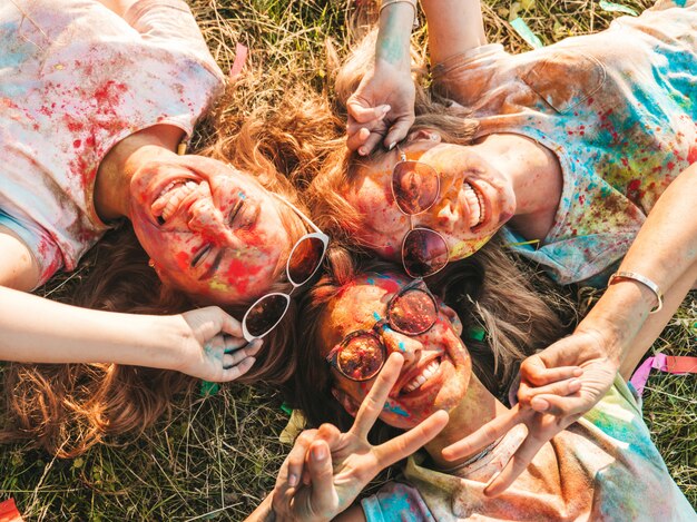 three beautiful smiling girls posing at holi party