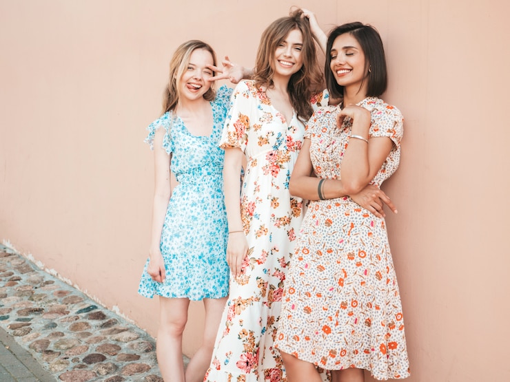 Free Photo three beautiful smiling girls in trendy summer sundress posing on the street