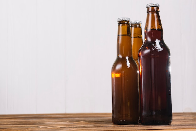 Three beer bottles on wooden desk