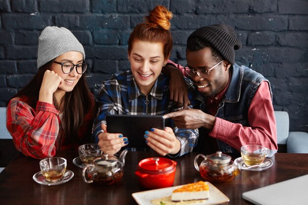 Three best friends of different races enjoying free wi-fi during lunch at restaurant