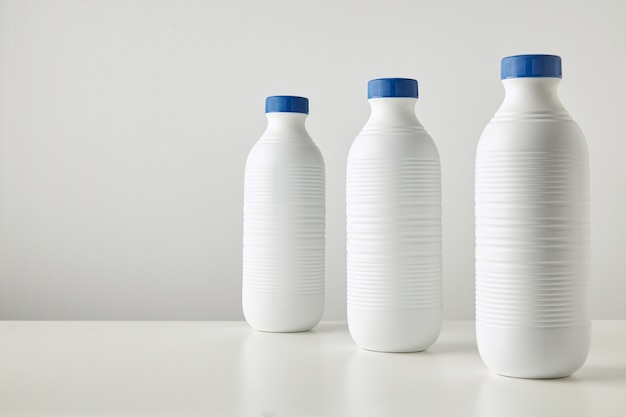 Three blank white plastic riffled bottles with blue caps in row isolated on table