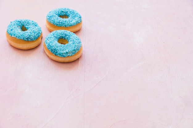 Free photo three blue donuts on pink backdrop