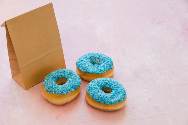 ピンクの背景に小包の3つの青いドーナツ
