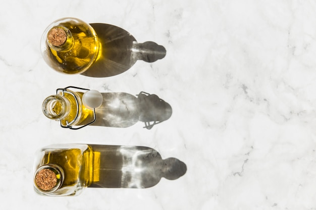 Three bottles of virgin healthy olive oil with shadow on floor