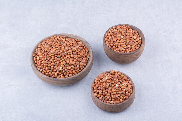 Three bowls full of red beans on marble surface