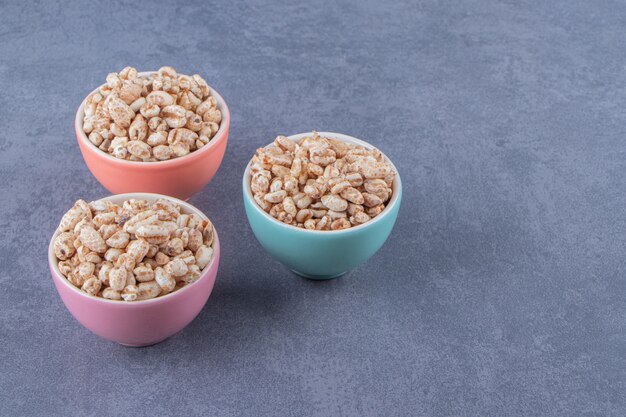 Three bowls of sweet muesli, on the marble background.