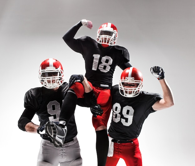 The three caucasian fitness men as american football players posing  as winners on white and rejoicing