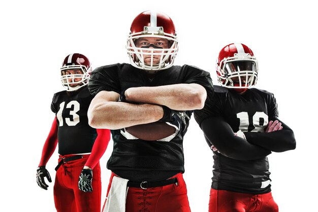 The three caucasian fitness men as american football players posing with a ball on white background