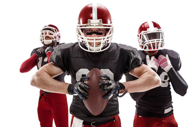 The three caucasian fitness men as american football players posing with a ball on white