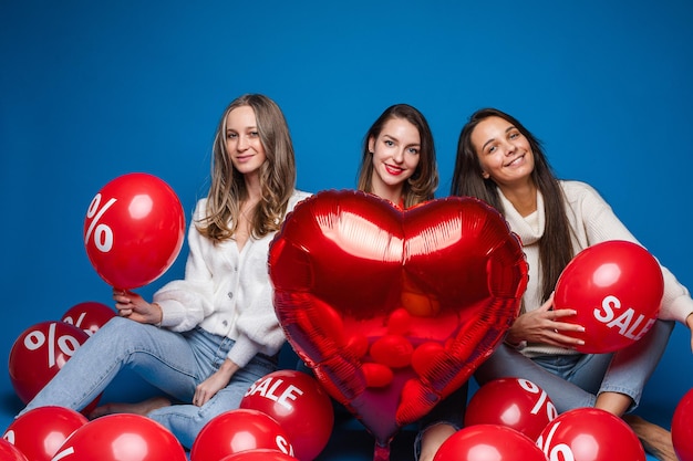 Three caucasian girlfriends rejoices of becoming sales in a shop