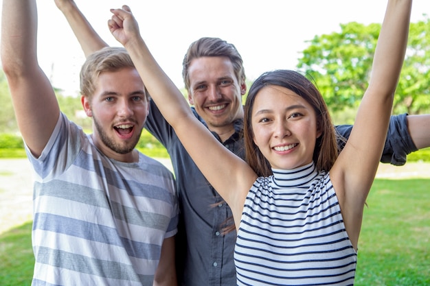 Three cheerful multiethnic friends raising hands