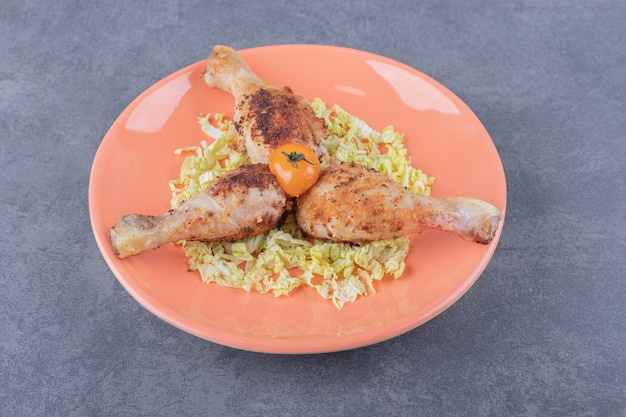 Three chicken drumsticks on orange plate.