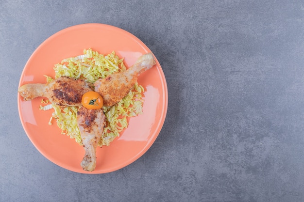 Three chicken drumsticks on orange plate.