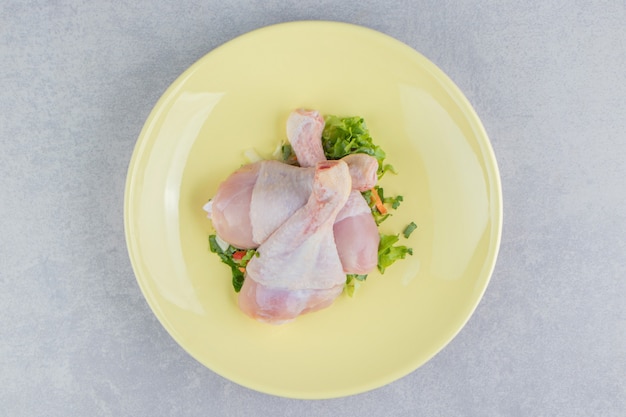 Three chicken leg and green, in the plate, on the white surface