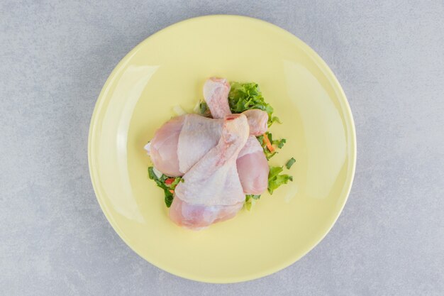 Три куриных ножки и зелень, в тарелке, на белой поверхности