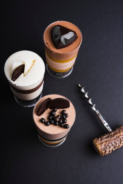 Три шоколадный мусс десерт в стеклянной банке на черном фоне