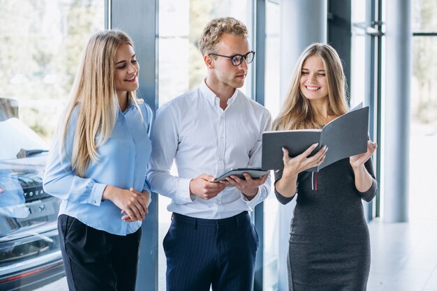 Three collegues working at a car showroom