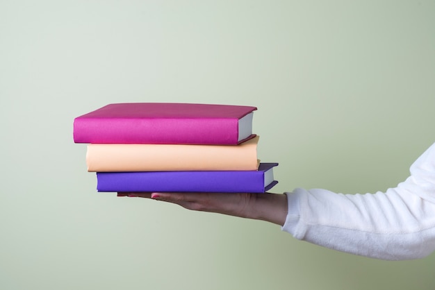 Three colored books on a hand