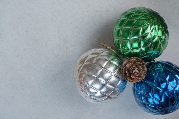 Three colorful Christmas balls with one pinecone on white background. High quality photo