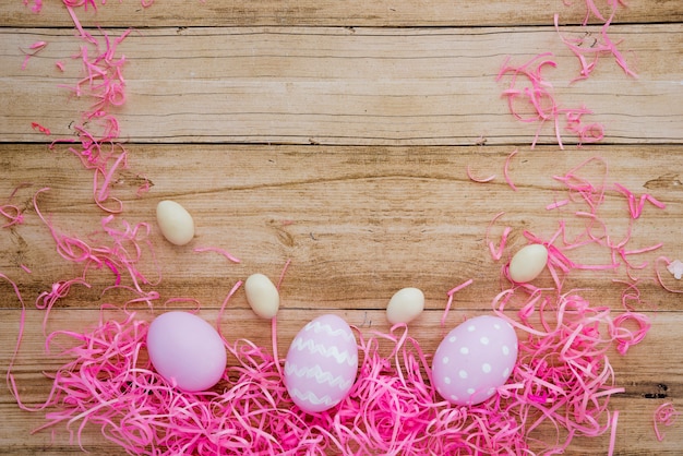 Free photo three colourful easter eggs with decorative straw on table