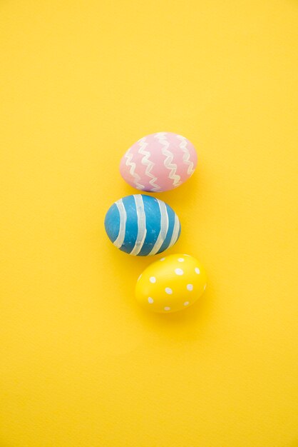 Three colourful Easter eggs on yellow table