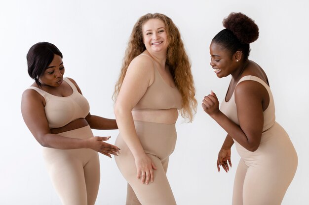 Three confident women posing together while wearing a body shaper