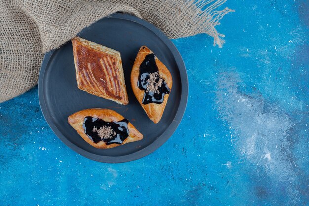 青い背景のタオルの横にあるボード上の3つのクッキー。高品質の写真