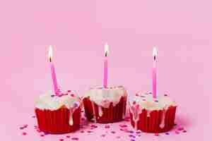Free photo three cupcakes with lit candles