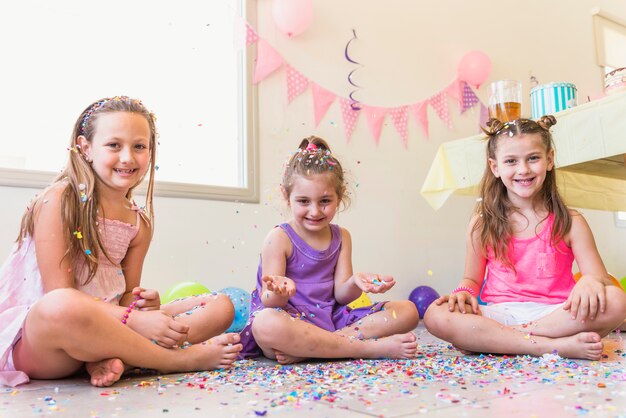 Three cute girls sitting on floor enjoying in a party