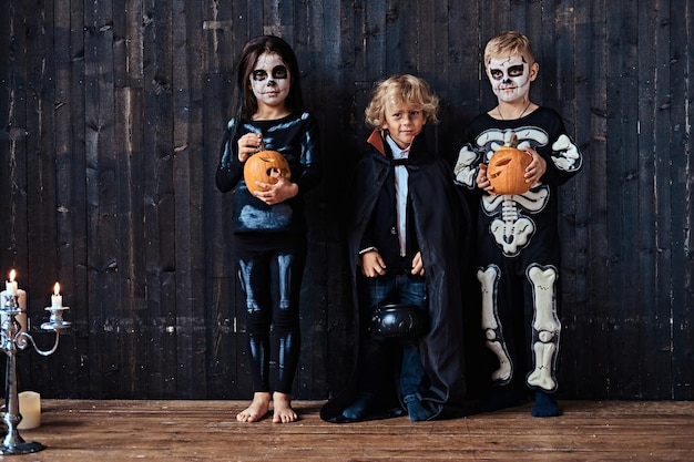 古い家でのハロウィーンパーティー中に怖い衣装を着た3人のかわいい子供たち。ハロウィーンのコンセプト。