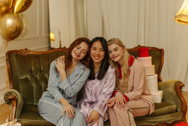 寝間着の3人のかわいい若い異人種間の女の子が家でパジャマパーティーをしている人々の感情の概念