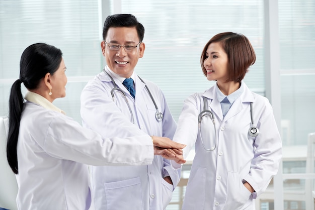 Three doctors giving unity gesture symbolizing teamwork