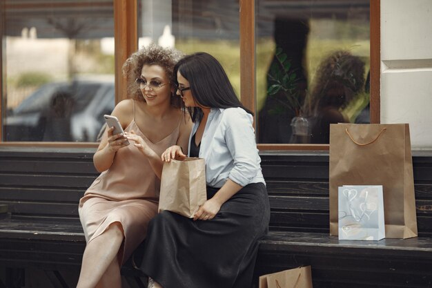 Three elegant women with shopping bags in a city