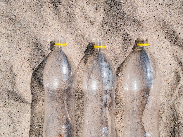 Three empty plastic bottle arrange in a row on sand