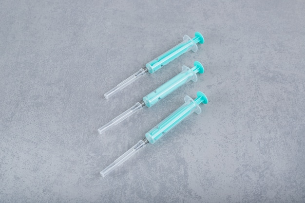 Three empty syringes on gray surface