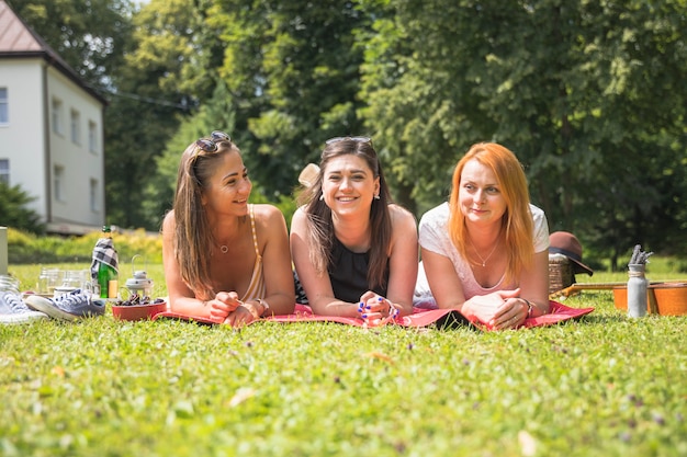 Three female friends lying on blanket in park