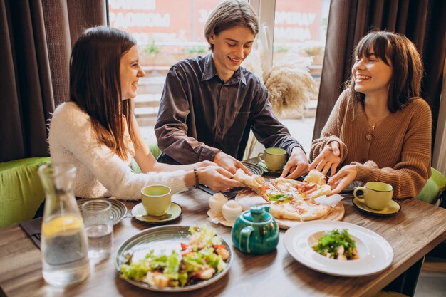 Three firends together eating pizza in a cafe