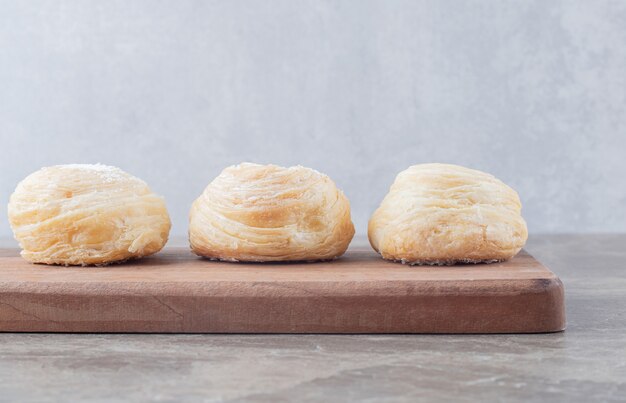 Three flaky cookies on a board on marble surface